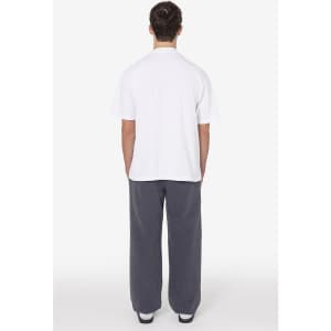 A person wearing a white t-shirt and grey heavy fleece sweatpants, standing with their back towards the viewer.