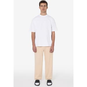 A man wears a casual white t-shirt and beige heavy fleece sweatpants, paired with black and white slide sandals.
