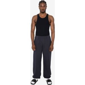 A pair of heavy fleece sweatpants in dark grey, worn by a model with a black tank top and sandals.