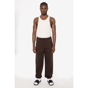 A model stands in brown heavy fleece sweatpants with an elastic waistband, paired with a white tank top and sandals.