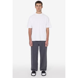 A grey pair of heavy fleece sweatpants displayed on a model wearing a white t-shirt and black sandals. The pants have a logo.