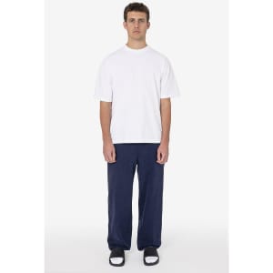 A model wearing a white t-shirt and navy heavy fleece sweatpants, paired with black and white footwear.