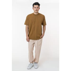 A man wearing a brown t-shirt and light pink heavy fleece sweatpants, standing against a white background.