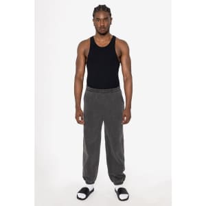 A model wearing grey heavy fleece sweatpants paired with a black tank top and sandals. The pants have a logo detail.