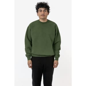 A green heavy fleece pullover is worn by a model standing in a neutral setting, with a logo visible on the garment.