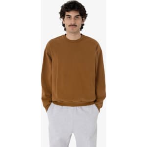A man wears a brown heavy fleece pullover paired with grey sweatpants. The pullover has a simple design and logo.