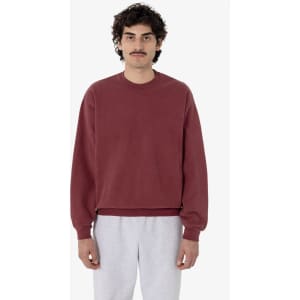 A maroon garment dye heavy fleece pullover with a relaxed fit and long sleeves, worn by a model.