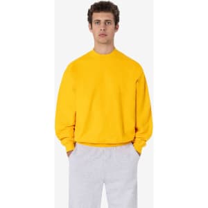 A yellow heavy fleece pullover displayed on a model, paired with grey trousers. The pullover features a logo.