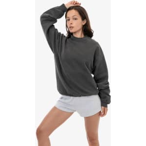 A woman poses wearing a grey heavy fleece pullover and light grey shorts, showcasing a casual style.
