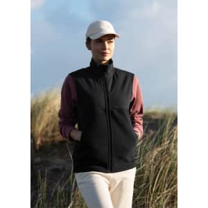 A unisex vest in black, worn over a pink long-sleeve top, complemented by a beige cap. Features a logo.