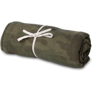 A rolled-up camouflage blanket tied with a white ribbon, featuring shades of green and brown.