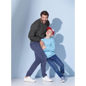 A man in a dark green jumper and a boy in a light blue jumper playfully pose against a blue background.