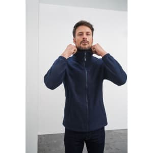 A navy full-zip fleece jacket on a man, featuring a high collar and zipped front. The jacket has a brand logo.