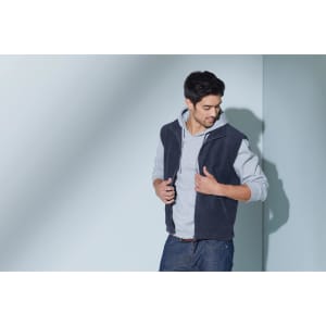 A fleece vest in navy blue, worn over a light grey hoodie, featuring a zip front and pockets.