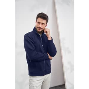 A men's navy jacket with a zip, featuring a high collar and pockets, worn by a model.