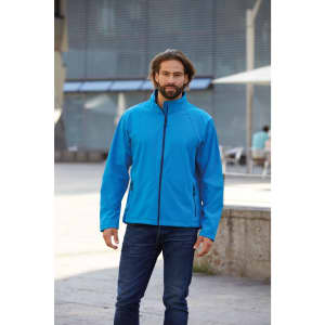 A man in a bright blue softshell jacket standing outdoors, paired with jeans. The jacket features a collar and zip.