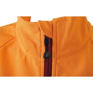 An orange softshell jacket featuring a zippered front and a high collar, with a small logo on the zipper.