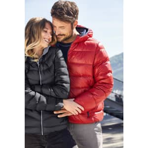 A black puffer jacket and a red puffer jacket modelled by a couple in a scenic outdoor setting. Each jacket features a hood.
