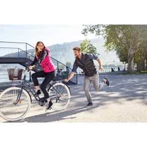 A pink ladies down vest is worn by a woman cycling, while a man runs alongside in a black vest.