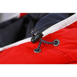 A close-up of a red vest featuring a black toggle and blue decorative cord detail.