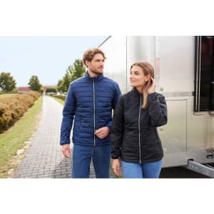 A navy blue padded jacket and a black padded jacket on two models, walking outdoors by a trailer.