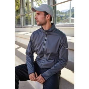 A men's sports softshell jacket in grey, featuring a zip front and a logo on the sleeve, worn by a model.