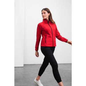 A red ladies softshell jacket with a zip front and two side pockets, paired with black pants.