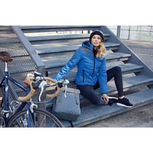 A blue puffer jacket with a hood, worn by a woman sitting on steps near a bicycle and a bag.