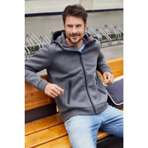 A men's hooded jacket in grey, featuring zippered pockets, worn by a man sitting on a wooden bench.