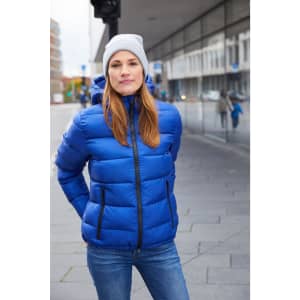 A blue padded jacket with a hood, paired with a grey beanie, worn by a woman standing outdoors.