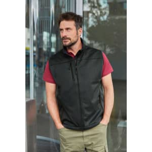 A black men's softshell vest is worn over a maroon shirt, featuring a zippered front and a logo.