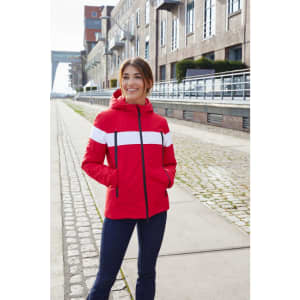 A red and white soft shell jacket with a hood, featuring a logo, worn by a woman standing outdoors.