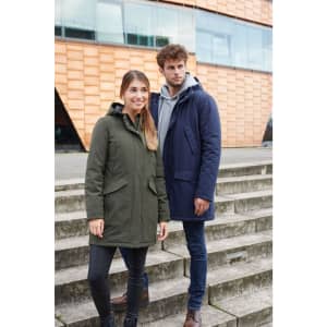 A green and a navy blue parka jacket on models standing on steps outside a modern building. Each jacket features a hood and branding.