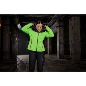 A bright green ladies all-weather jacket with a hood is worn by a person indoors, with a dark backdrop.