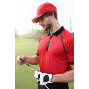 A man in a red zip polo shirt stands on a golf course, holding a golf club, wearing a matching cap and glove.
