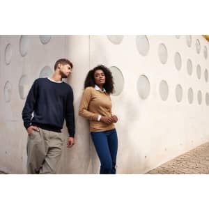 A navy blue and a tan knitted jumper are displayed on models standing against a textured white wall with circular cutouts.