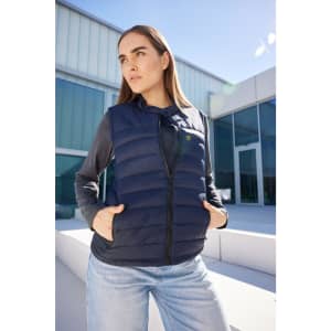 A ladies padded vest in navy blue, featuring a front zip and pockets, worn over a long-sleeved top.