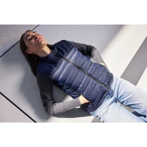 A navy padded vest with a zip front, paired with a long-sleeved grey top, laid against a light background.