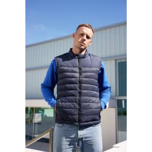 A navy padded vest is displayed, featuring a zip front and a model wearing a blue long-sleeve top in the background.