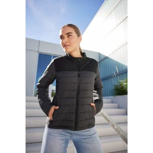 A padded jacket in black, featuring a sleek design, with a logo, worn by a model outdoors.