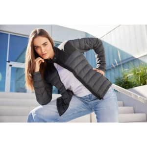 A padded jacket for ladies in dark grey, featuring a zip front and a fitted design, set against a modern backdrop.