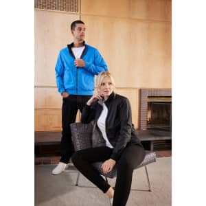 A blue blouson jacket worn by a man, alongside a black jacket worn by a woman sitting on a chair. Both have logos.