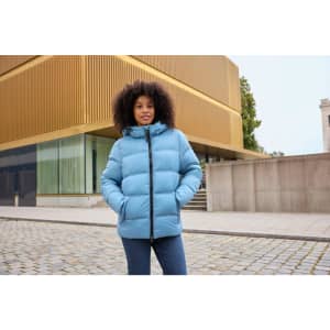 A light blue puffer jacket with a hood, featuring a zip front and side pockets, worn by a woman outdoors.