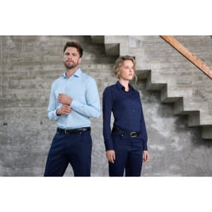 A light blue men's shirt and a navy women's shirt displayed on models against a concrete backdrop with stairs.