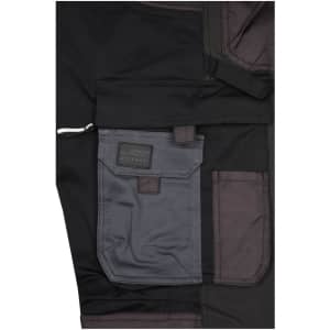 Close-up of black workwear stretch-pants featuring grey pockets and a branded label.