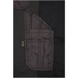 A close-up view of black workwear stretch-pants featuring multiple pockets and a branding label.
