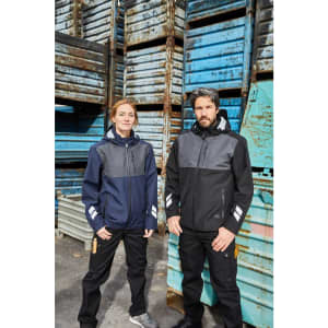 Two models wearing Hardshell Workwear Jackets in navy and black, standing against a backdrop of blue and grey crates.