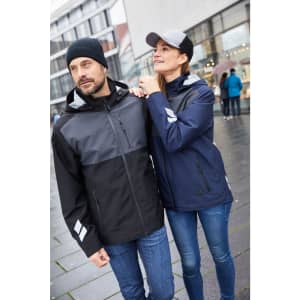 A hardshell workwear jacket in black and navy, featuring reflective details, worn by a man and a woman outdoors.