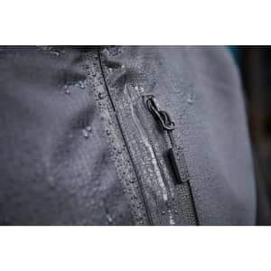 A close-up of a grey hardshell workwear jacket featuring a zip and water droplets on the fabric, with a logo present.