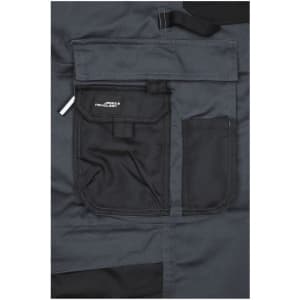 A close-up of dark grey workwear pants featuring a black bib and multiple front pockets, including a logo.